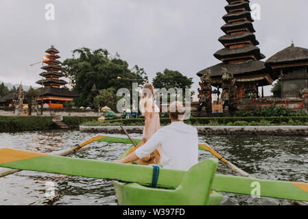 Jeune beau couple pagayer sur un bateau en bois à Pura Ulun Danu Bratan, Bali - Touristes explorer Bali Banque D'Images