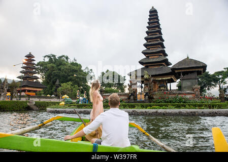 Jeune beau couple pagayer sur un bateau en bois à Pura Ulun Danu Bratan, Bali - Touristes explorer Bali Banque D'Images