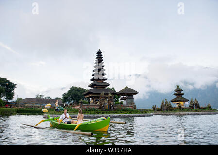 Jeune beau couple pagayer sur un bateau en bois à Pura Ulun Danu Bratan, Bali - Touristes explorer Bali Banque D'Images