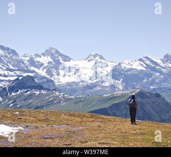 Femme hiker with backpack hiking sur l'herbe brune sur plateau avec des montagnes couvertes de neige à haute altitude dans l'arrière-plan. Banque D'Images