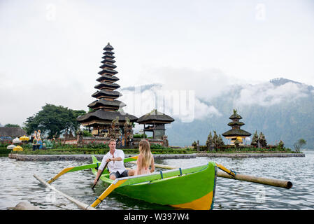 Jeune beau couple pagayer sur un bateau en bois à Pura Ulun Danu Bratan, Bali - Touristes explorer Bali Banque D'Images