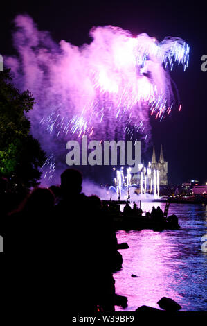 Cologne, Allemagne. Le 13 juillet, 2019. Les spectateurs suivent le grand feu d'artifice sur les rives du Rhin à la musique de Jacques Offenbach dans le cadre de la "Cologne". Credit : Henning Kaiser/dpa/Alamy Live News Banque D'Images