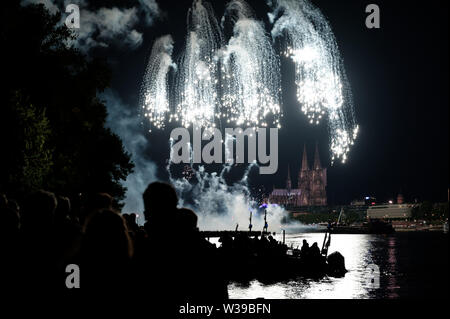 Cologne, Allemagne. Le 13 juillet, 2019. Les spectateurs suivent le grand feu d'artifice sur les rives du Rhin à la musique de Jacques Offenbach dans le cadre de la "Cologne". Credit : Henning Kaiser/dpa/Alamy Live News Banque D'Images