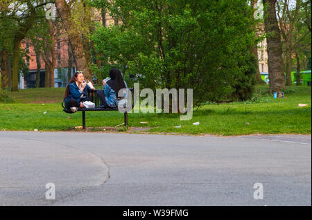 Manchester, Royaume-Uni - 22 Avril 2019 : deux femmes gaies sur un banc profitant de leurs boissons au Whitworth Park Banque D'Images