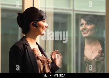 Businesswoman smiling avec dispositif mains libres Banque D'Images