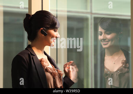 Businesswoman smiling avec dispositif mains libres Banque D'Images