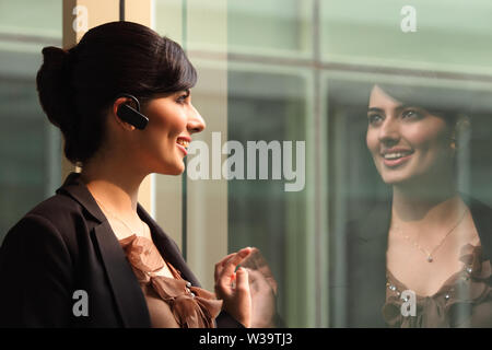 Businesswoman smiling avec dispositif mains libres Banque D'Images