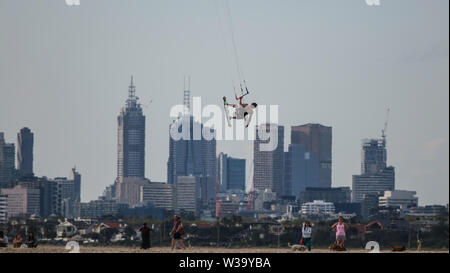 La pendaison du ciel à Melbourne. Un kiteboarder vole haut sur Port Phillip Bay avec les toits de Melbourne dans l'arrière-plan. Banque D'Images