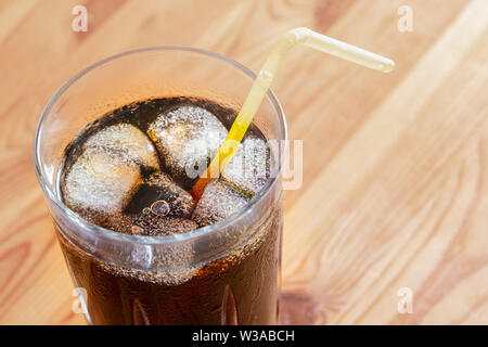 Boisson glacée dans un verre, vue du dessus. Verre de boisson gazeuse fraîche avec de la glace sur une table en bois, close-up shot Banque D'Images