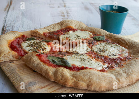 Des pizzas au four à la maison. La farine de blé entier, de la sauce tomate, mozzarella et padano fromages, tomates cerises, origan et l'ail. Banque D'Images