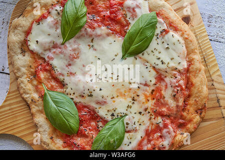 Des pizzas au four à la maison. La farine de blé entier, de la sauce tomate, mozzarella et padano fromages, tomates cerises, origan et l'ail. Banque D'Images