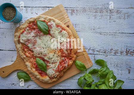 Des pizzas au four à la maison. La farine de blé entier, de la sauce tomate, mozzarella et padano fromages, tomates cerises, origan et l'ail. Banque D'Images