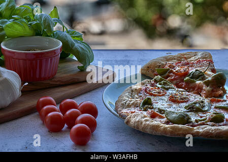 Des pizzas au four à la maison. La farine de blé entier, de la sauce tomate, mozzarella et padano fromages, tomates cerises, origan et l'ail. Banque D'Images