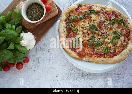 Des pizzas au four à la maison. Sauce tomate, mozzarella et padano fromages, tomates cerises et petits poivrons épicés, l'origan et l'ail. Banque D'Images