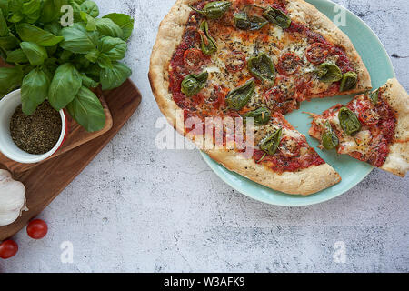 Des pizzas au four à la maison. Sauce tomate, mozzarella et padano fromages, tomates cerises et petits poivrons épicés, l'origan et l'ail. Banque D'Images