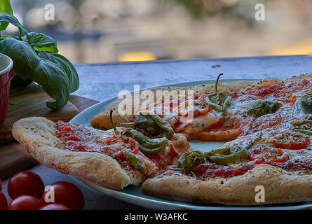 Des pizzas au four à la maison. Sauce tomate, mozzarella et padano fromages, tomates cerises et petits poivrons épicés, l'origan et l'ail. Banque D'Images