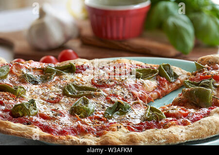 Des pizzas au four à la maison. Sauce tomate, mozzarella et padano fromages, tomates cerises et petits poivrons épicés, l'origan et l'ail. Banque D'Images