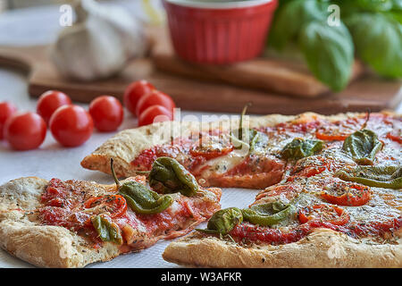 Des pizzas au four à la maison. Sauce tomate, mozzarella et padano fromages, tomates cerises et petits poivrons épicés, l'origan et l'ail. Banque D'Images