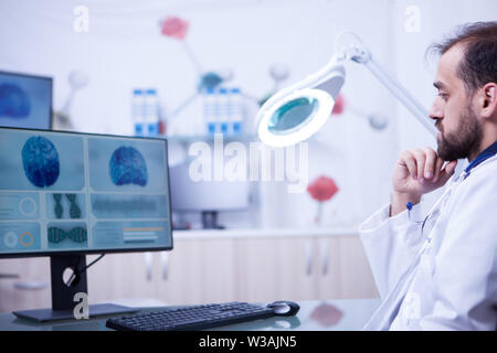 Jeune médecin barbu faisant un examen du cerveau dans un hôpital moderne. Radiologue dans un laboratoire hospitalier. Banque D'Images