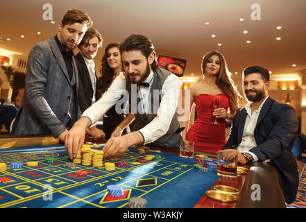 Un jeune homme avec des amis fait des paris sur la roulette dans un casino. Les jeux de hasard dans un casino. Banque D'Images