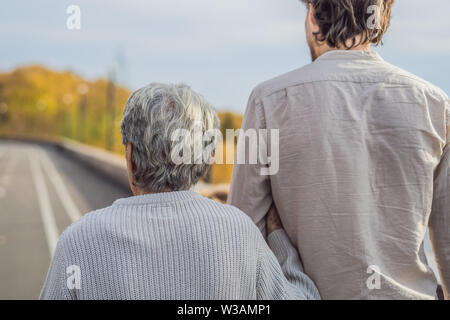 Un couple de personnes âgées des promenades dans le parc avec un homme assistant ou petit-fils adultes. La prise en charge des personnes âgées, le bénévolat Banque D'Images