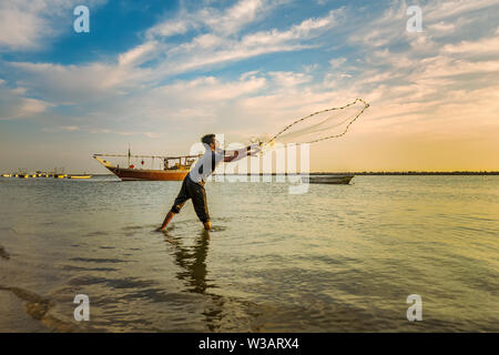 Silhouettes des pêcheurs jetant filet de pêche pendant le coucher du soleil à Dammam Arabie Saoudite bord Banque D'Images