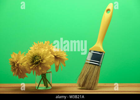 Nouveau pinceau et de fleurs dans un vase sur une table en bois rouge. Très beau wall background derrière. Banque D'Images