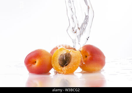 Une vague d'eau claire tombe sur l'abricot sur un fond blanc Banque D'Images