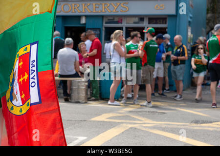 Le jour du match à Killarney, comté de Kerry, Irlande. Drapeau de football gaélique de Mayo et supporters devant le bar Corkerys sur High Street, Killarney, comté de Kerry, Irlande Banque D'Images