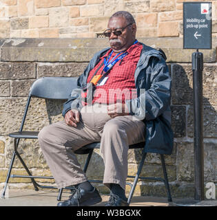 Un vieil homme noir, assis sur une chaise, sommeillant sous le chaud soleil du printemps sur le château d'Édimbourg, promenade. L'Écosse, au Royaume-Uni. Banque D'Images