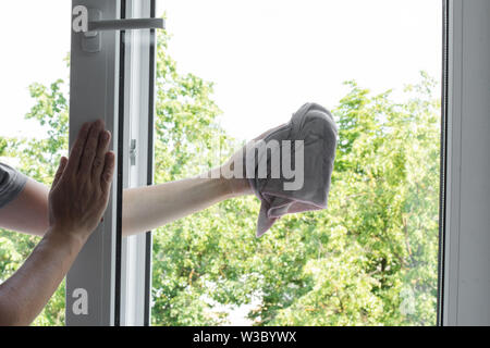 Travailleur homme gardant chiffon en main et fenêtre d'essuyage Banque D'Images