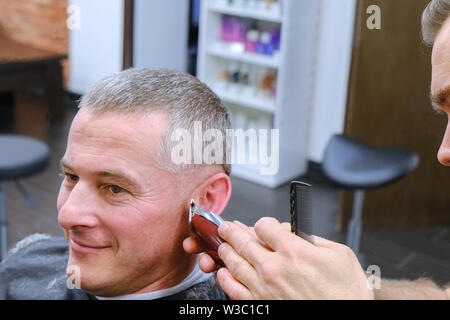 Maître de coupes au travail. Heureux les gars se coupe par coiffure Banque D'Images