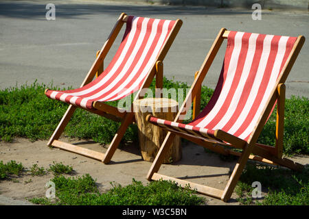 Libre de deux confortables fauteuils rouges et blancs dans le parc et d'un moignon entre eux Banque D'Images