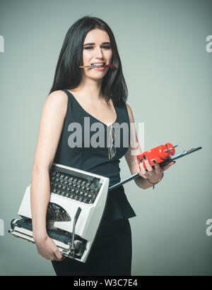 Professeur dame porte typewriter réveil et calendrier. Concept de multitâche. Dame réussite du multitâche. Girl détient stylo dans les dents. Juste-à-temps Banque D'Images