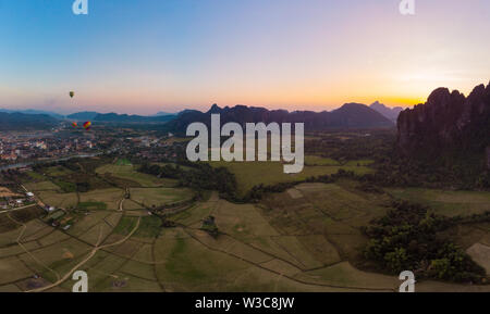 Antenne : Vang Vieng backpacker travel destination au Laos, en Asie. Coucher de soleil sur des falaises et des pinacles, rizières valley, paysage magnifique. Banque D'Images