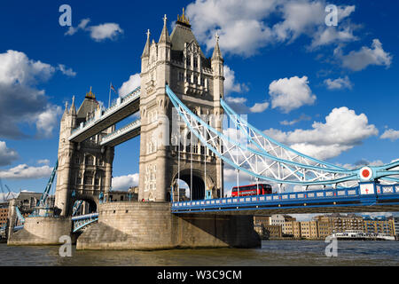 Tours en pierre double tour de pont sur la rivière Thames à London avec bus rouge et bleu et blanc suspension bridge et des taux élevés d'un passage piéton Banque D'Images