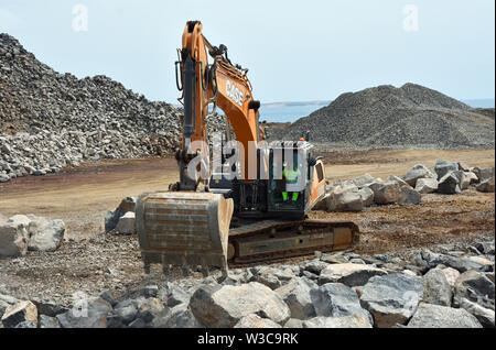 Digger déménagement grands blocs de construction sur site. Banque D'Images