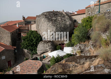 Une vue panoramique de la coupe des maisons historiques en pierre construit en entre des rochers massifs dans le village de Monsanto, Portugal. Banque D'Images