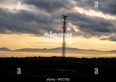 Une seule ligne d'alimentation pendant le coucher du soleil pôle avec les montagnes et le brouillard à l'arrière-plan. Banque D'Images