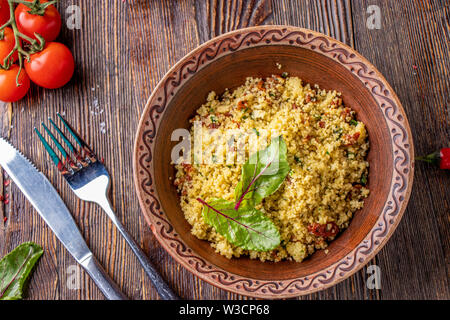 Couscous dans un bol avec de l'huile d'olive et tomates séchées sur fond de bois, de la cuisine orientale, photo horizontale, Close up Banque D'Images