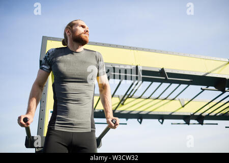 Une sérieuse barbu dans les corps de poids holding tshirt sur barres parallèles et bénéficiant d'une formation d'entraînement Banque D'Images