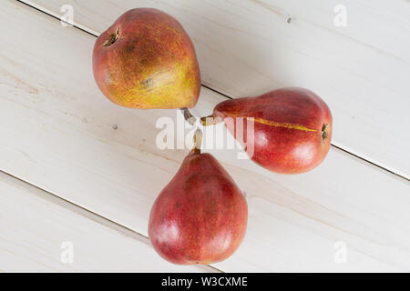 Groupe de trois entiers et frais poire rouge anjou flatlay sur bois blanc Banque D'Images