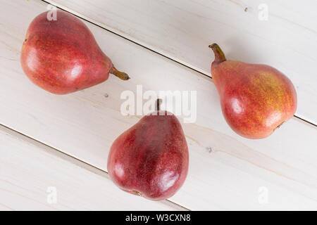 Groupe de trois entiers et frais poire rouge anjou flatlay sur bois blanc Banque D'Images