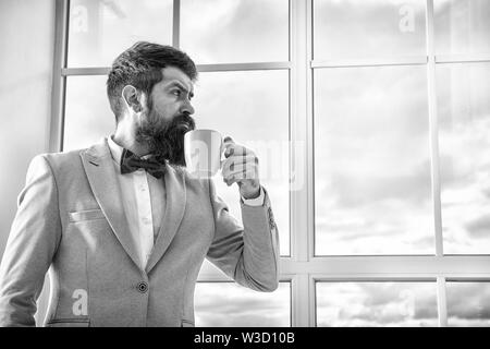 Bon café le matin. homme barbu grave de boire du café. businessman en costume officiel. la vie moderne. business man à fenêtre. succès futur. matin inspiration. copie espace. Profiter de café du matin. Banque D'Images