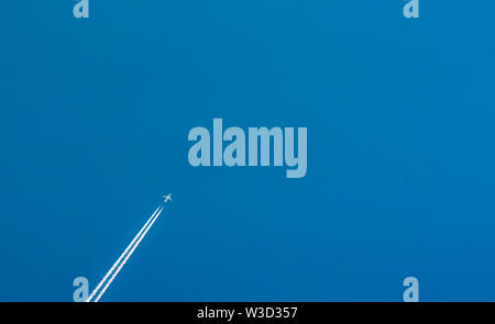 Avion avec condensation blanc pistes. Jet sur ciel bleu clair avec traînée de vapeur. Voyage par avion concept. Des sentiers à partir de gaz d'avion Banque D'Images