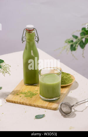 Thé vert matcha latte en bouteille en verre et tasse sur fond blanc Banque D'Images