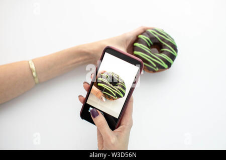 Woman photographing with smartphone donut Banque D'Images