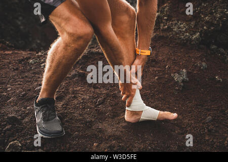 Homme coureur tenant jambe blessée close-up et de la souffrance à la douleur. Blessure à la jambe. Entorse ligament ou tendon lors de l'exécution de l'extérieur. Le bandage de compression Banque D'Images