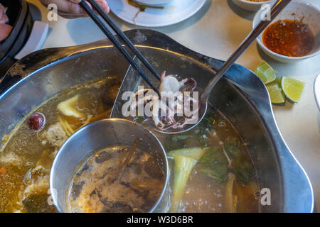 Les gens de l'Asie à l'aide de baguettes pour manger des fruits de mer asiatiques potée Banque D'Images