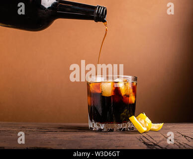 Dans un verre de glaçons brandy whisky versé. Boisson alcoolisée forte sur un fond sombre. Focus sélectif. Copier l'espace. Banque D'Images